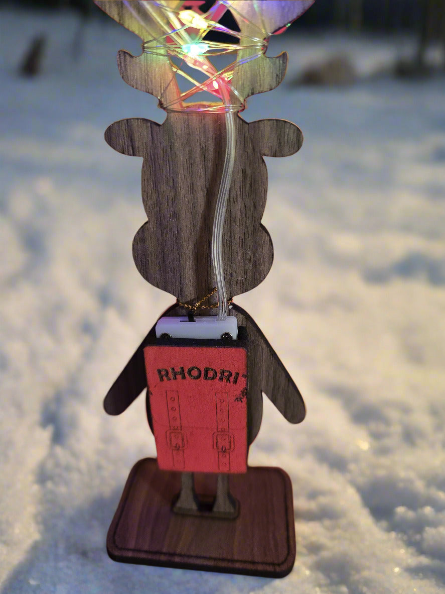 Wooden reindeer decoration with a small backpack labeled 'RHODRI'